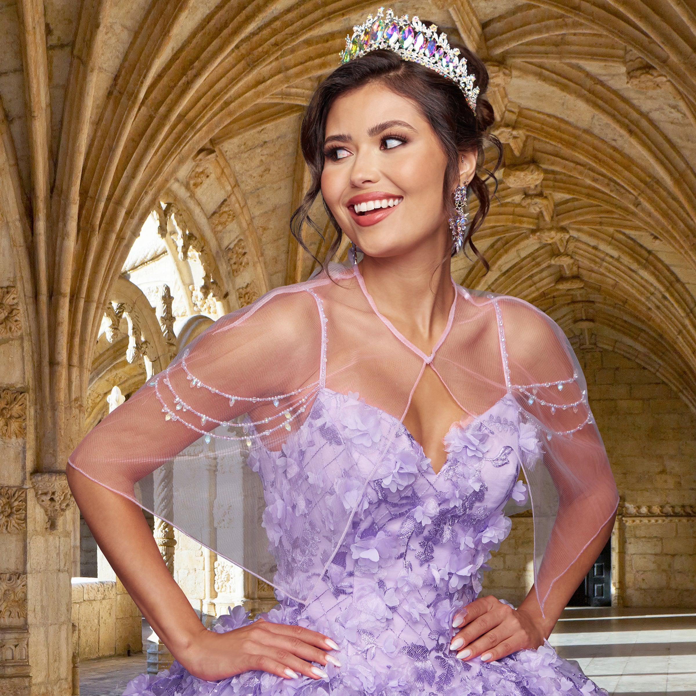 A woman wearing the Quinceañera Sample Dress QF105 and a beaded tiara stands in a stone archway, smiling and looking to the side.
